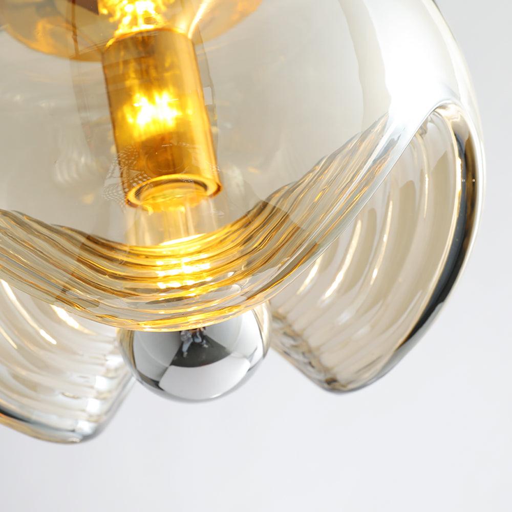 Close view of this Clérachic pendant's amber glass shade lit from within, its ribbed folds glowing warmly around a gold socket.