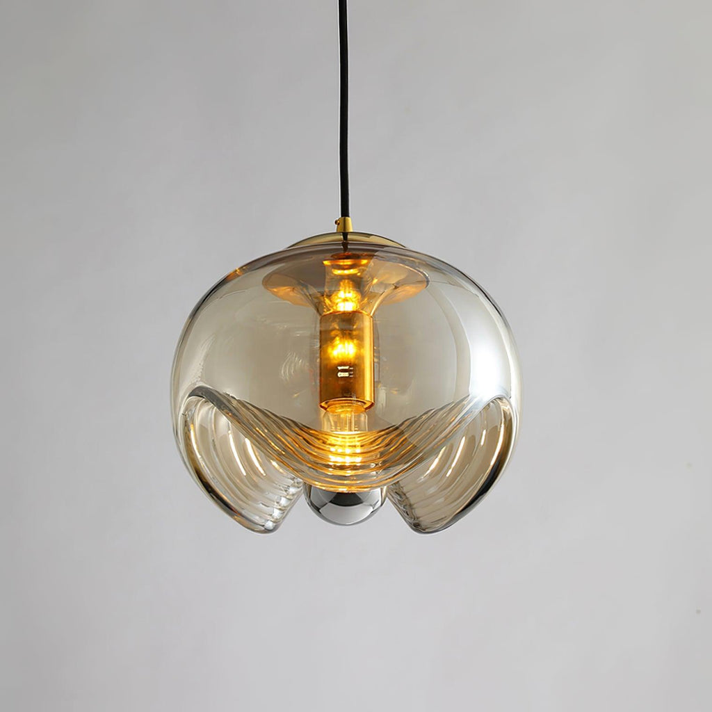 This Clérachic pendant's amber glass shade and gold frame hang lit against a plain grey backdrop, its ribbed underside fully visible.