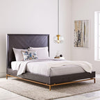 Above a charcoal upholstered bed with brass legs, this Clérachic pendant's clear glass shade and silver frame hang near a framed abstract artwork.