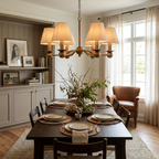 Hanging over a wood dining table set for a meal, this brushed brass Clérachic chandelier lights built-in shelving nearby.
