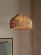 Close view of this Clérachic pendant's diagonal weave and fringed rim, lit softly against a plain wall.