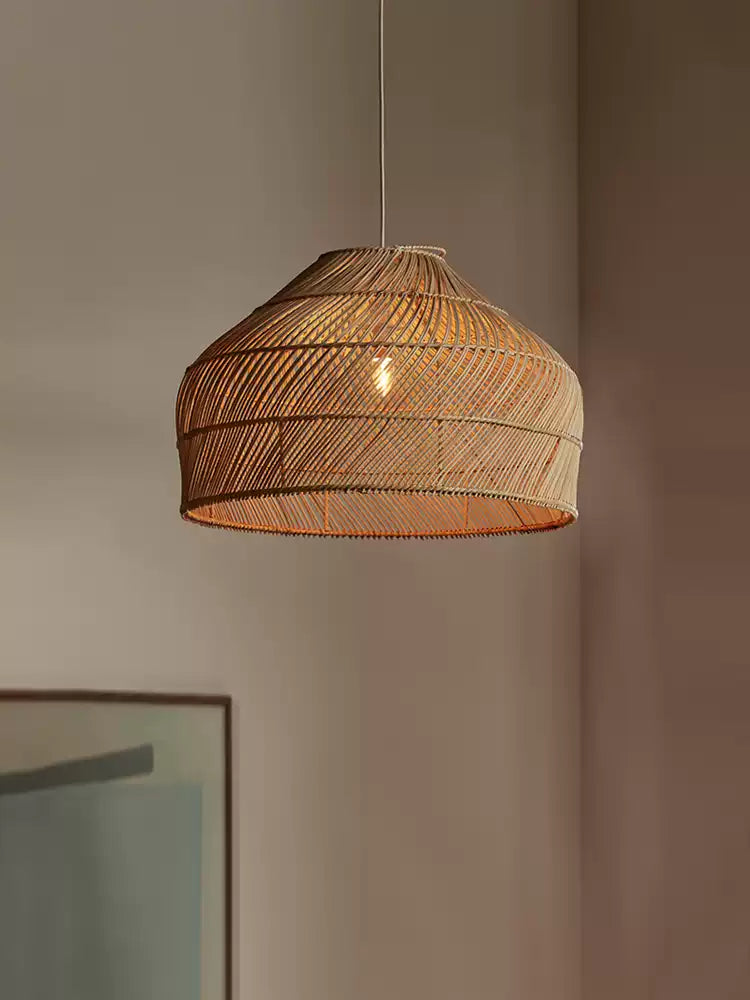 Close view of this Clérachic pendant's diagonal weave and fringed rim, lit softly against a plain wall.