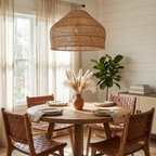 This Clérachic pendant hangs over a round wood table set with leather-woven chairs and a jute rug underfoot.