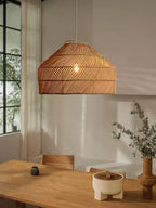 Near a black-framed window, this Clérachic pendant hangs above a wood table with a small potted plant beside it.