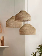 This Clérachic pendant in three sizes hangs above a console table holding a vase, a plant nearby.