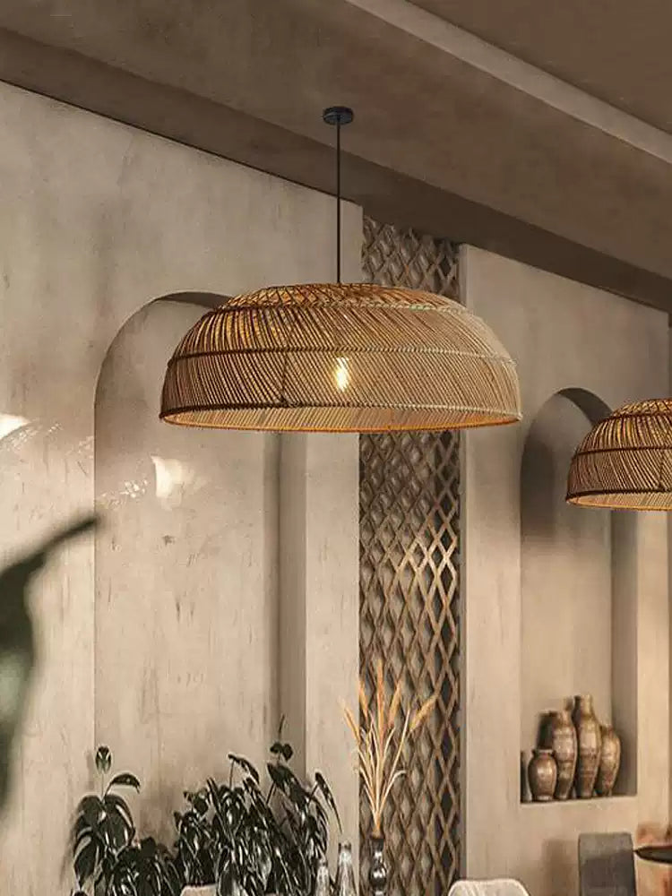 In a hallway with a stone-textured wall, this Clérachic pendant hangs beside an arched niche holding potted plants.
