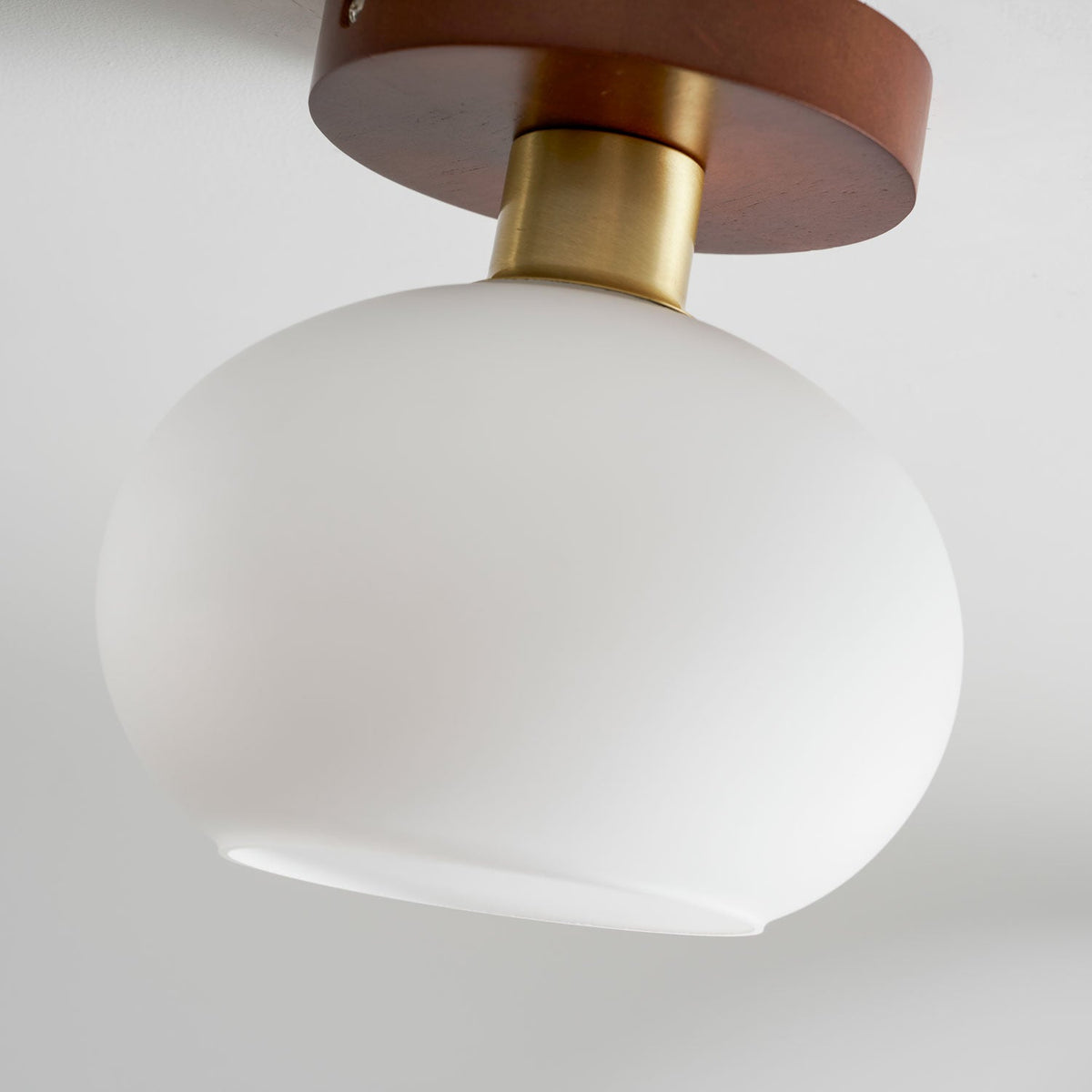 A tight crop shows the walnut canopy and copper fitting of this Clérachic ceiling light, its shade unlit below.