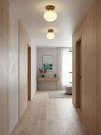 Down a wood-panelled hallway, two of these Clérachic ceiling lights glow warm above a console table.