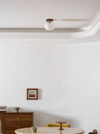 A round table and framed print sit below this unlit Clérachic ceiling light along a crown-moulded ceiling.