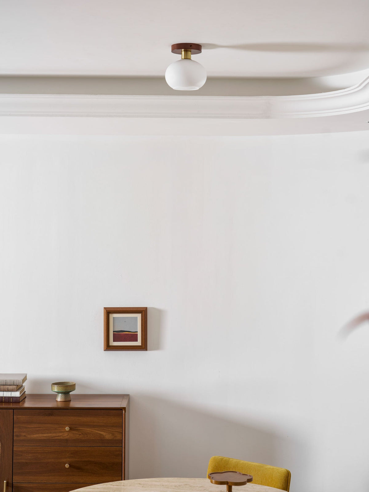 A dresser set with a cup sits below this unlit Clérachic ceiling light near a round table.