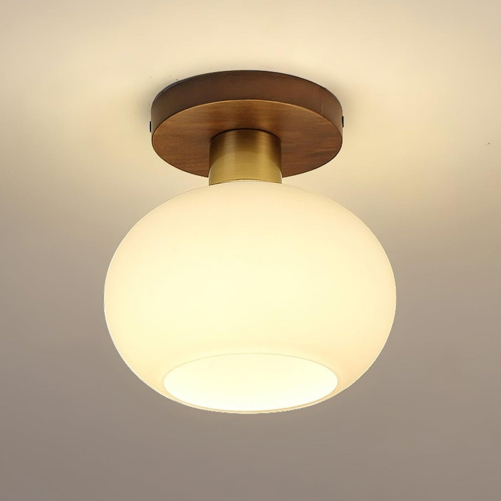 At an angle, this lit Clérachic ceiling light shows warm light glowing through its opal glass shade.