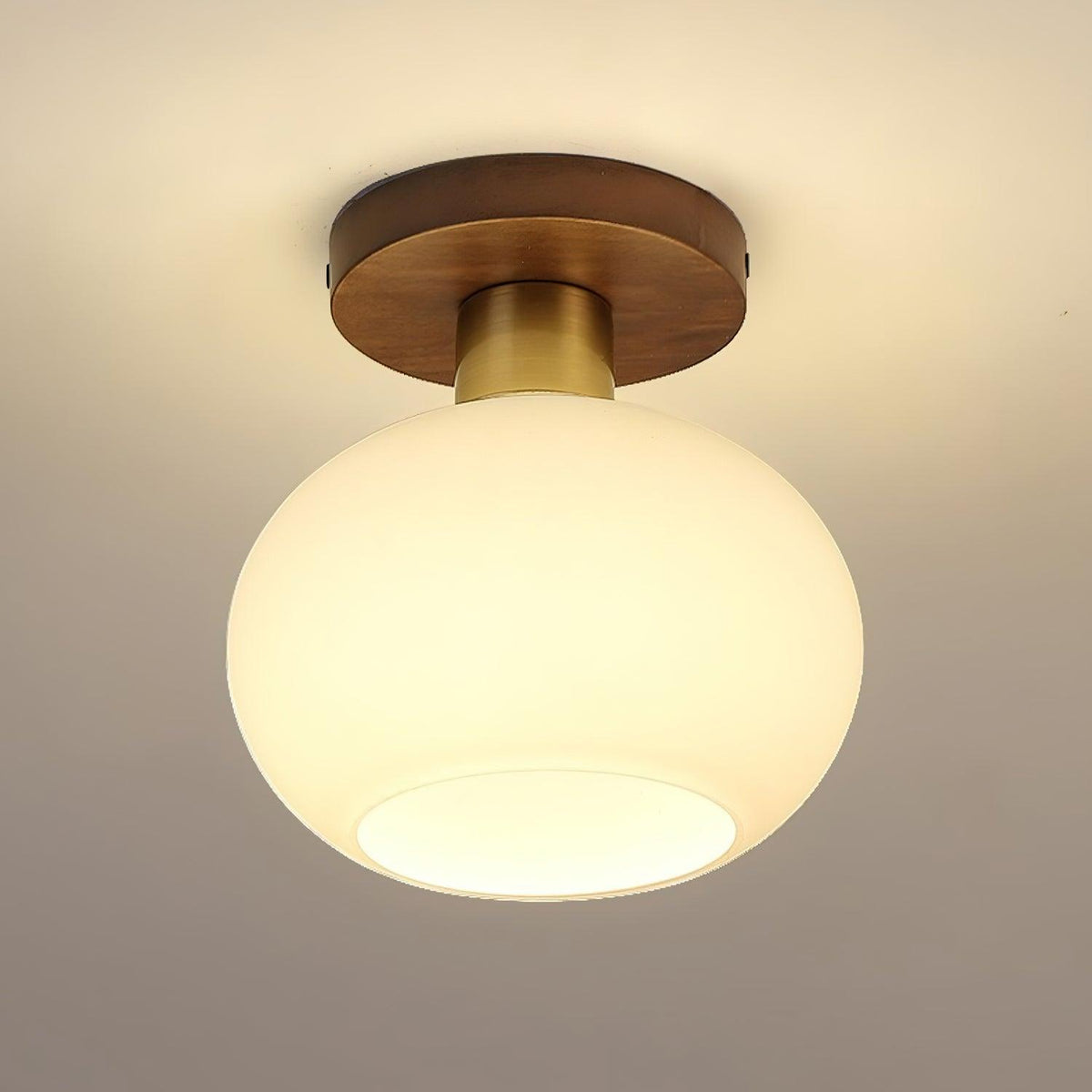 At an angle, this lit Clérachic ceiling light shows warm light glowing through its opal glass shade.