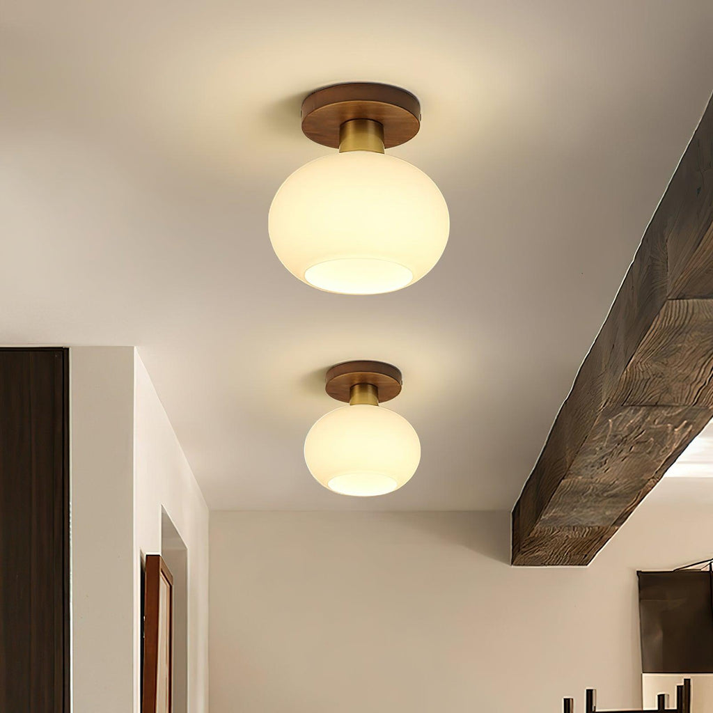 A wooden ceiling beam frames two of these Clérachic ceiling lights, glowing warm down a hallway.