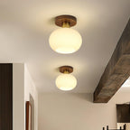 A wooden ceiling beam frames two of these Clérachic ceiling lights, glowing warm down a hallway.