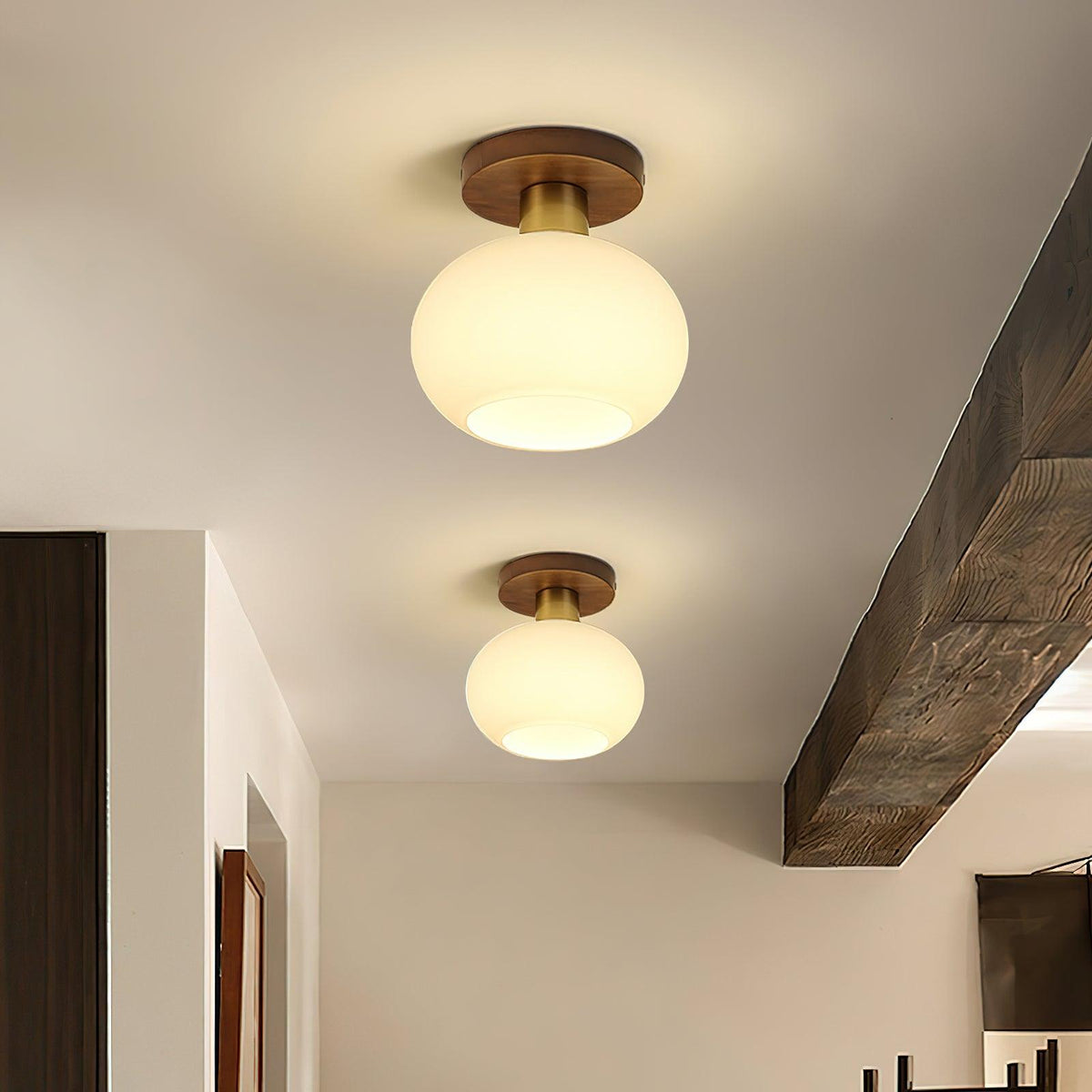 A wooden ceiling beam frames two of these Clérachic ceiling lights, glowing warm down a hallway.
