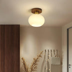 Coat hooks and dried pampas grass hang in a hallway lit by this Clérachic ceiling light.