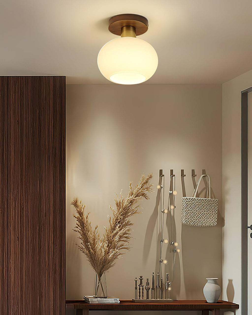 String-lit coat hooks and a console table sit beneath this Clérachic ceiling light, glowing warm in an entryway.
