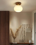 String-lit coat hooks and a console table sit beneath this Clérachic ceiling light, glowing warm in an entryway.
