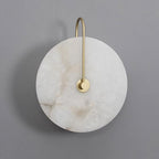 Unlit Elaris wall light in gold on grey, the stone disc marked with warm brown veining.