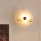 Closer view of the gold Elaris wall light lit on a white wall above a framed patterned artwork.