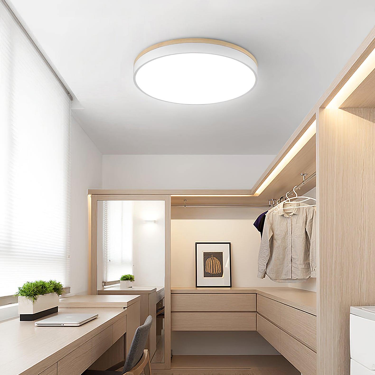 Round white ceiling light lighting a cozy bedroom