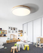 Round wooden ceiling light shown at an angle when lit
