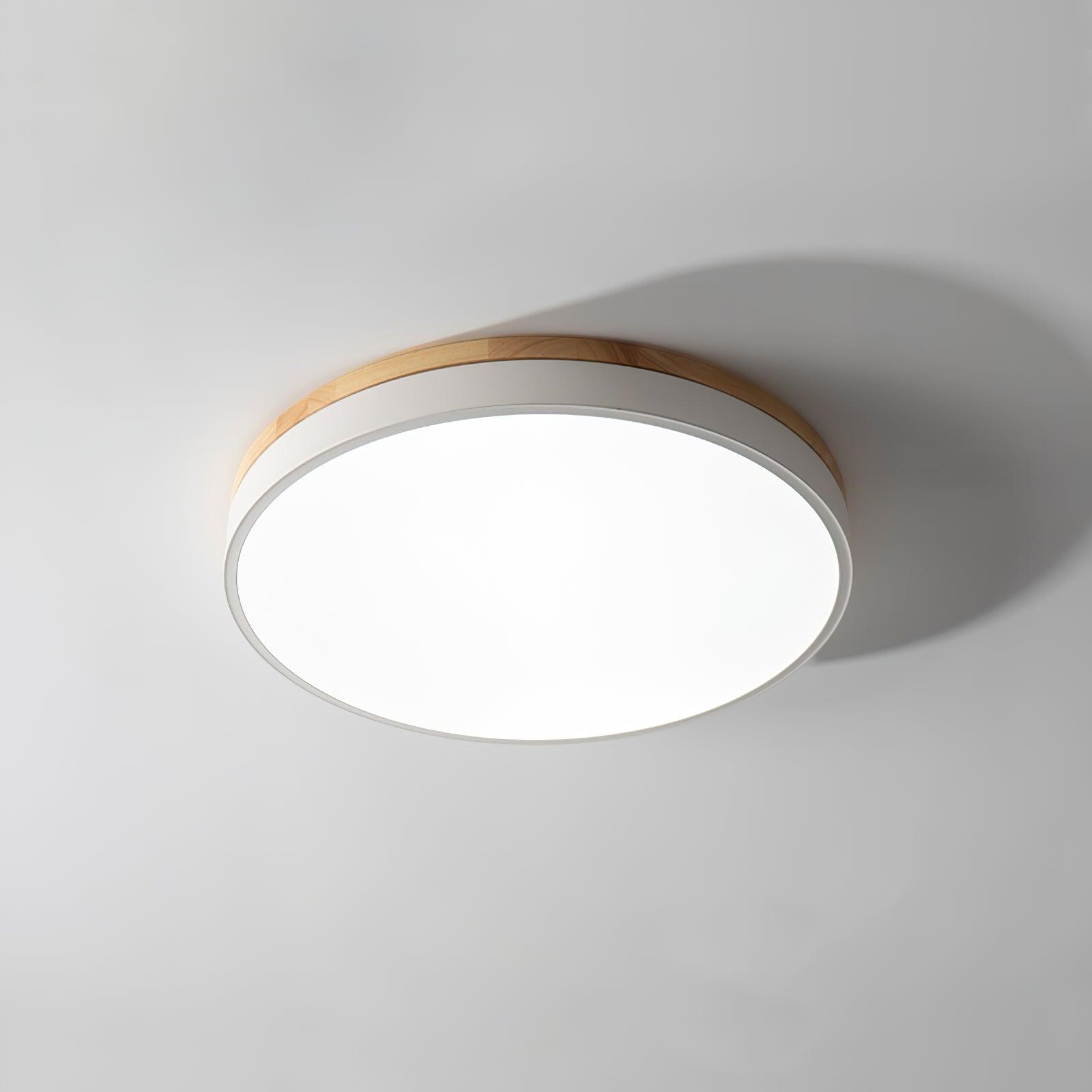 Round wooden ceiling light lit in a bright bedroom