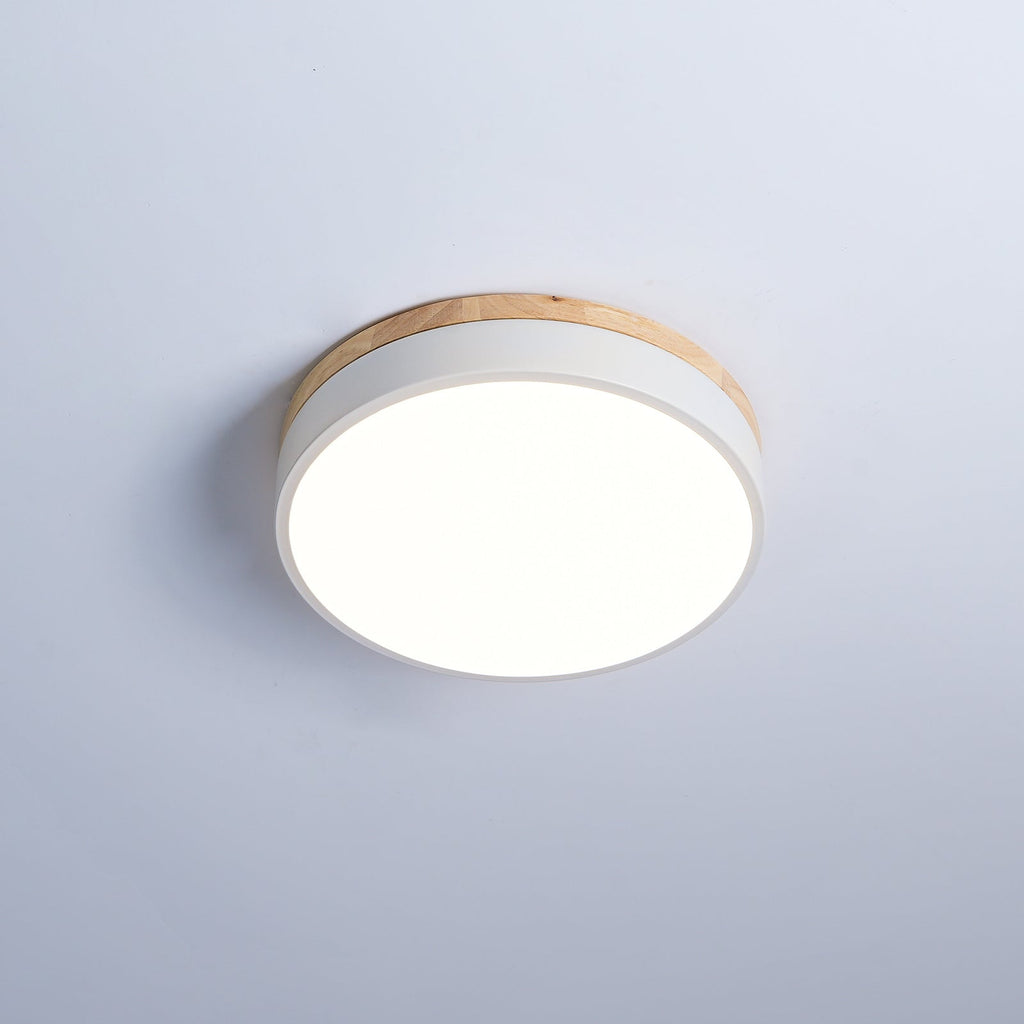 Round wood and white flush mount ceiling light glowing softly