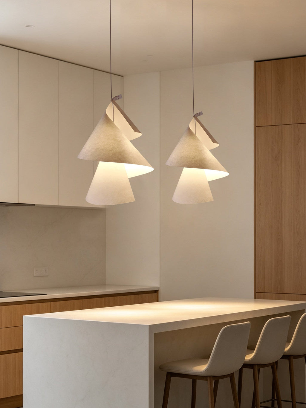 Above a white kitchen island with barstools, two textured cone pendants hang from this Clérachic fixture.