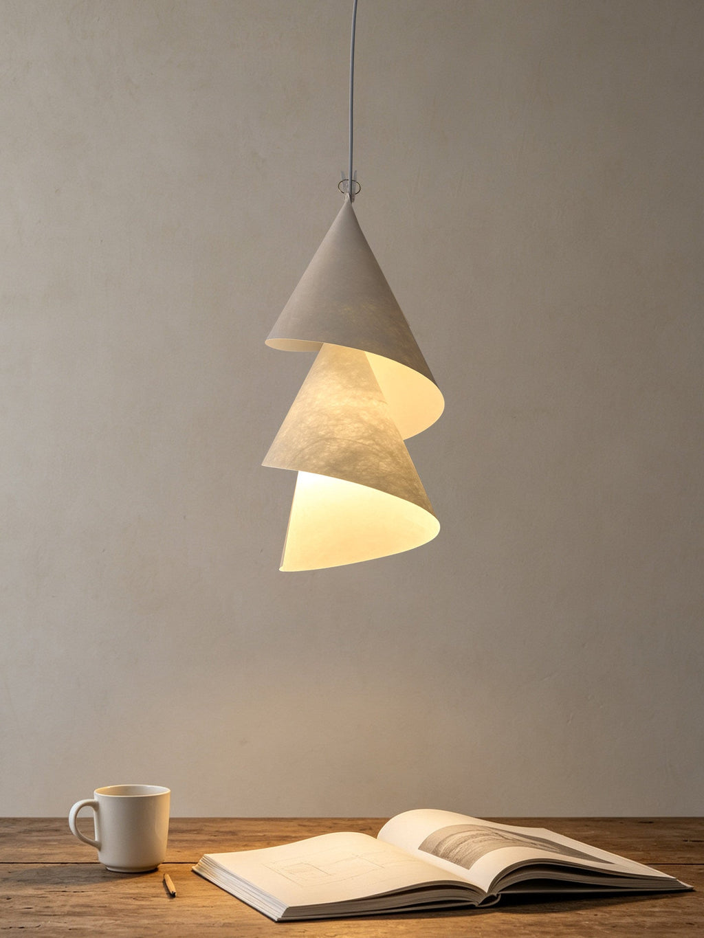 Above a small table set with a mug and an open notebook, this Clérachic pendant hangs alone.
