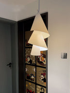 In a narrow hallway beside a patterned door, three paper cones spiral down this Clérachic pendant.