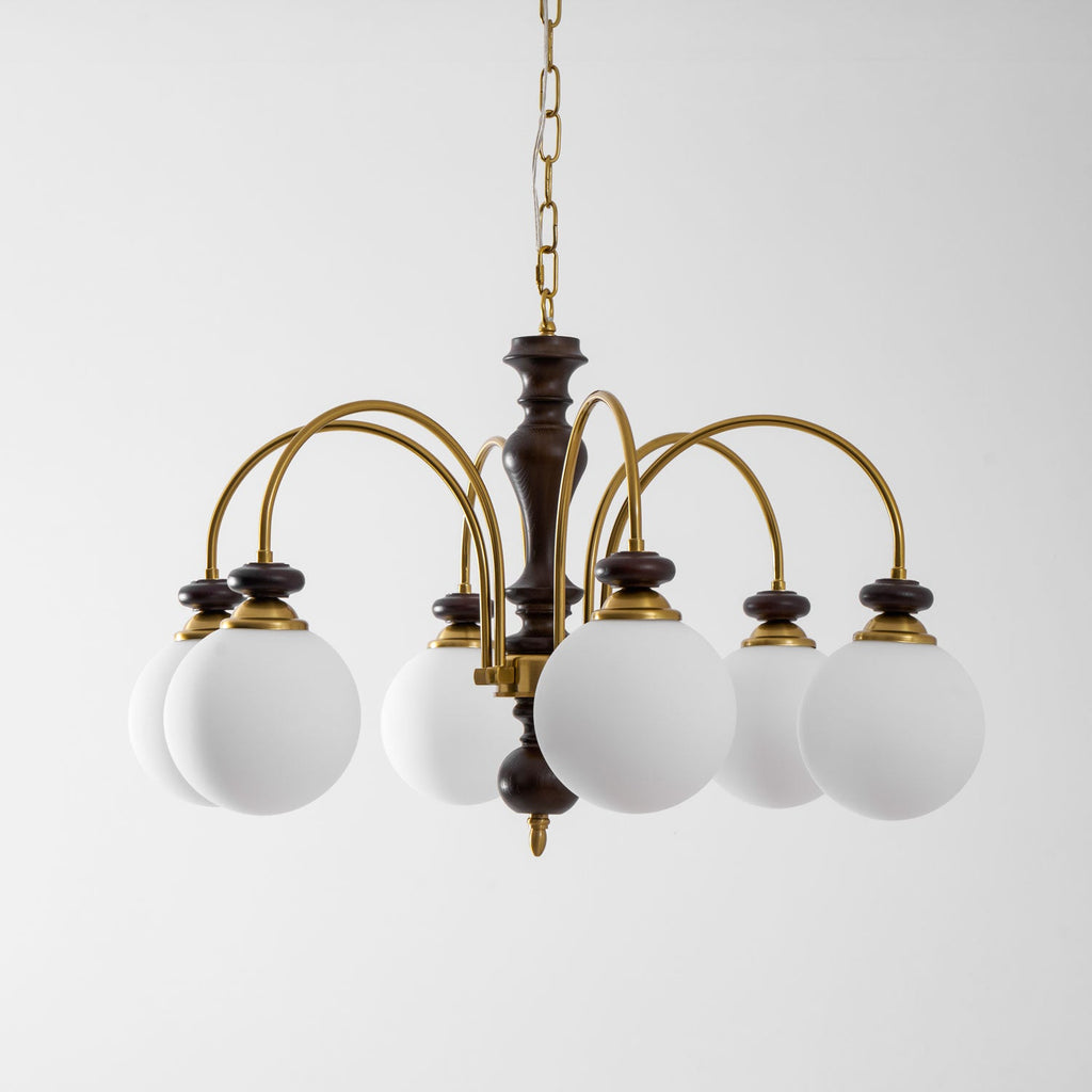 Walnut gold chandelier shown lit over a wooden table