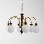 Walnut gold chandelier shown lit over a wooden table