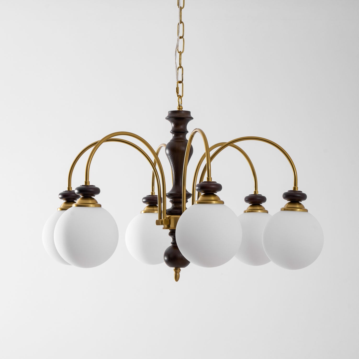 Walnut gold chandelier shown lit over a wooden table