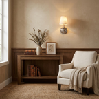 This brushed nickel Clérachic wall sconce glows above a console styled with a vase, books and a framed photo.