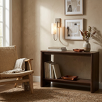 Framed art and a vase sit beneath a nickel Clérachic sconce lighting the wall above a console table.