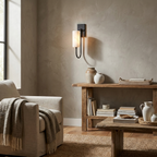 Above a reclaimed-wood console table, a black Clérachic sconce glows beside an armchair draped with a throw.