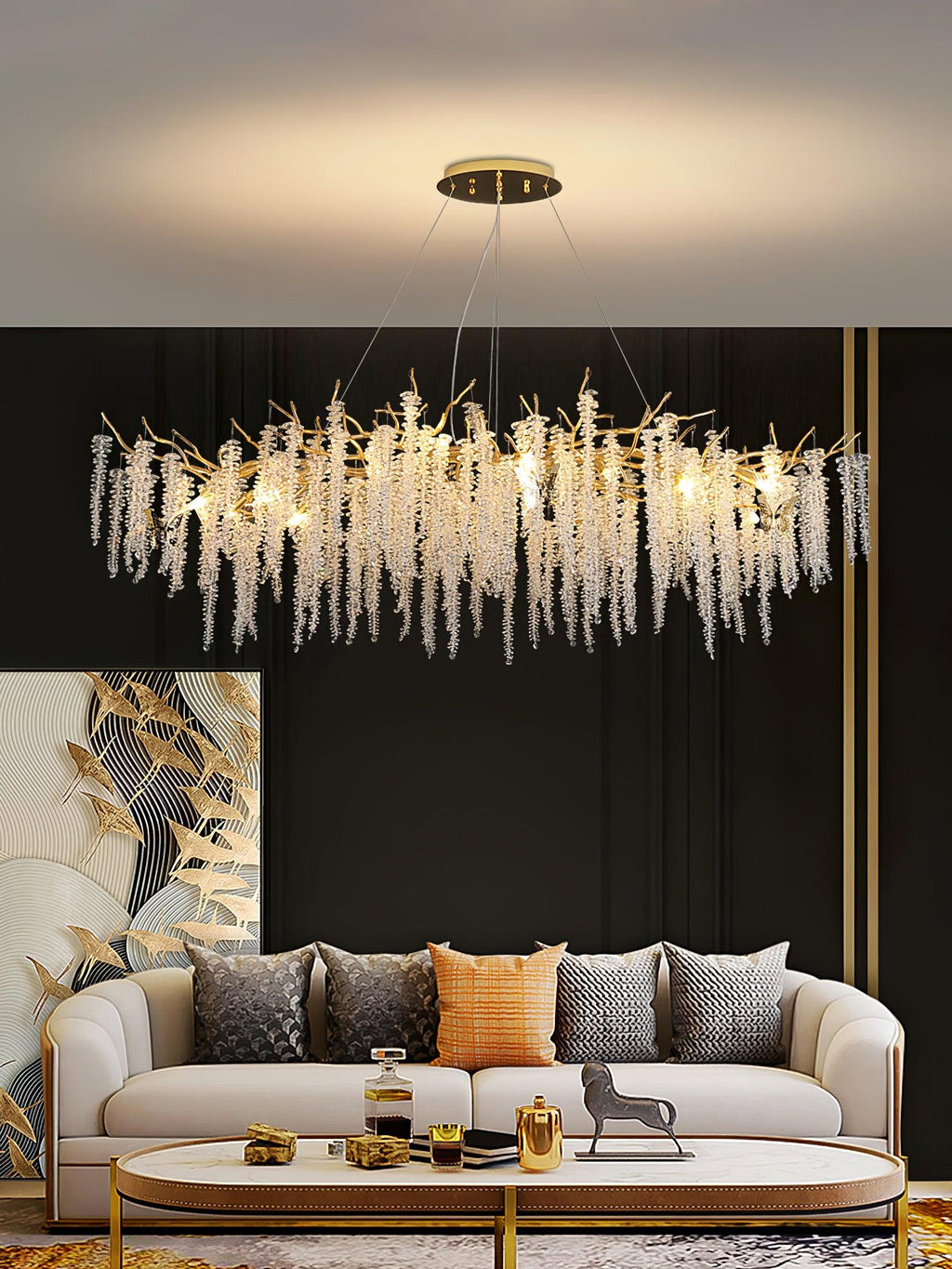 Wider view of the same room, the chandelier's crystal strands lit above a low coffee table.