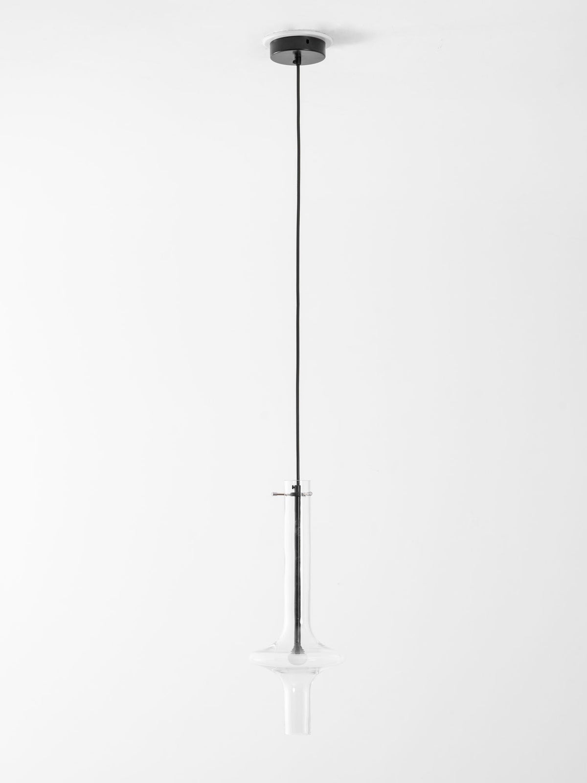 A single black-stemmed Clérachic pendant in clear glass hangs unlit on a long cord against a plain grey backdrop.