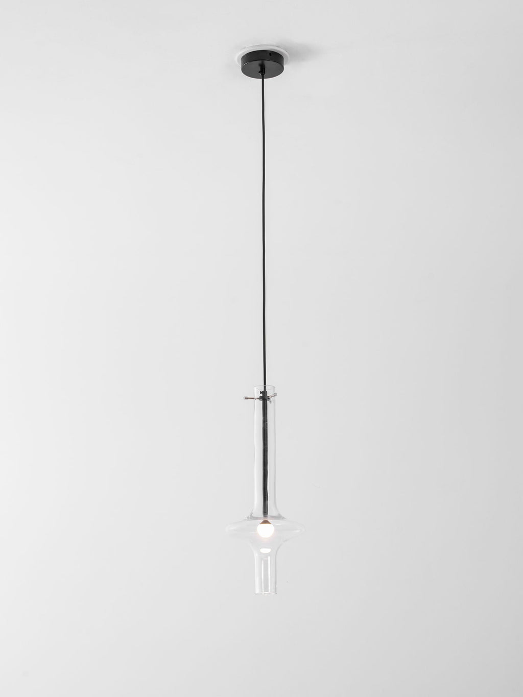 A single black-stemmed Clérachic pendant in clear glass hangs unlit on a short cord close to its black ceiling canopy.