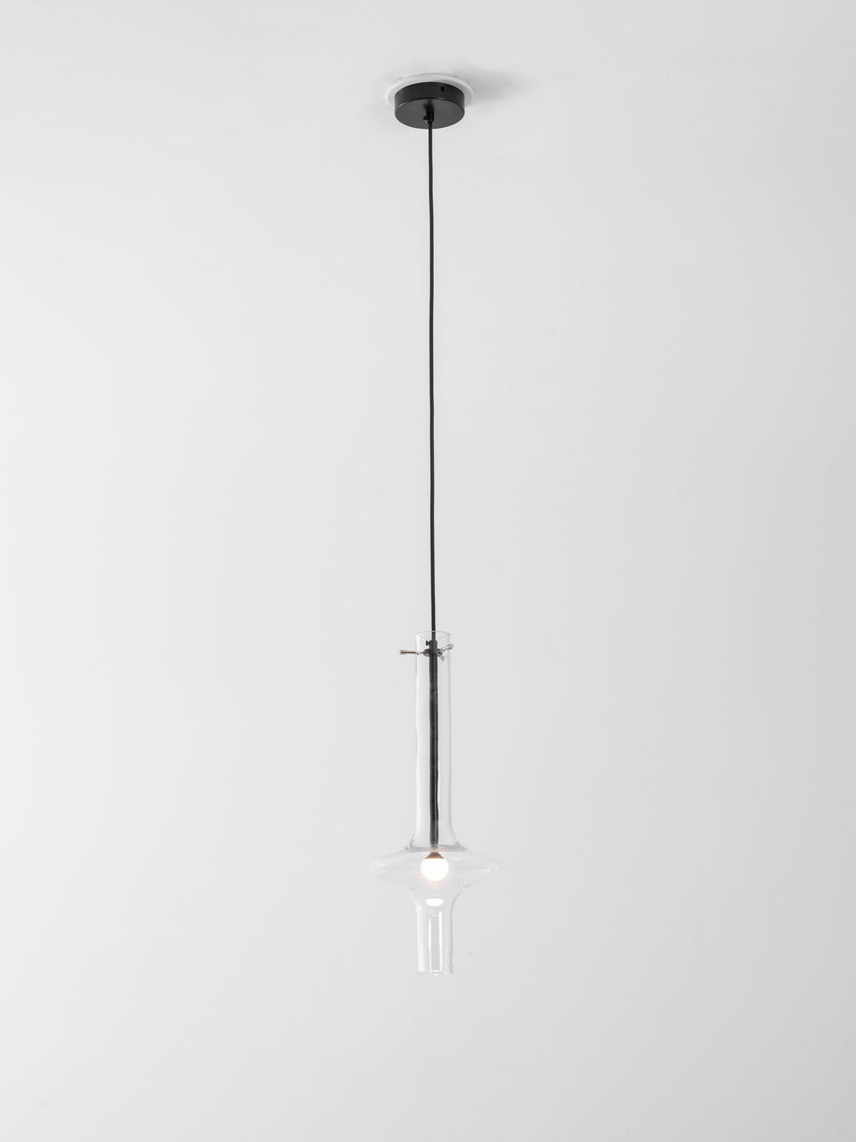 A single black-stemmed Clérachic pendant in clear glass hangs unlit on a short cord close to its black ceiling canopy.