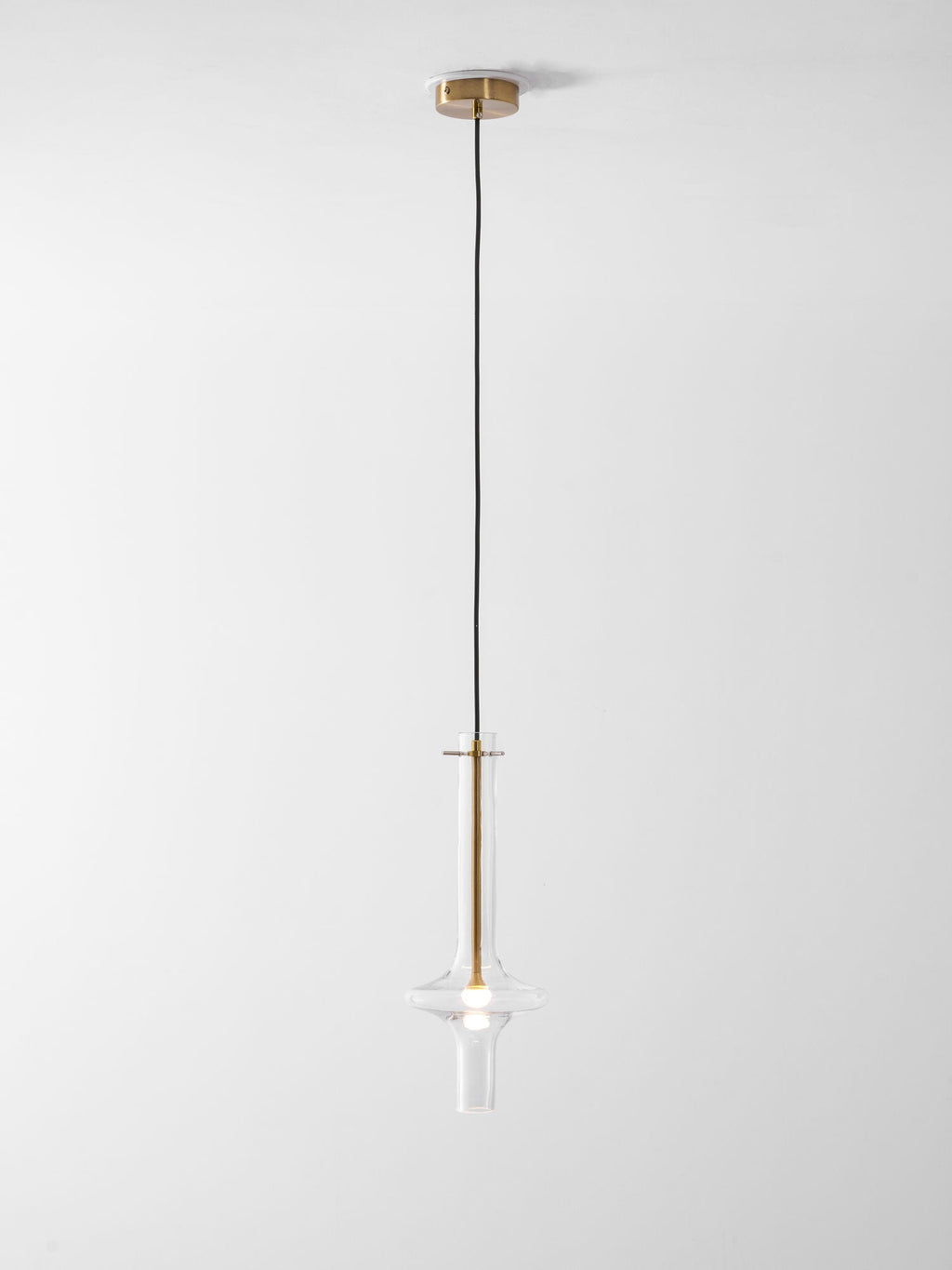 A single gold-stemmed Clérachic pendant in clear glass hangs unlit on a shorter drop against a plain white backdrop.
