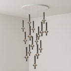 Black-stemmed Clérachic pendants trail low in a spiralling pattern from a round canopy, lit in the corner of a grey room.
