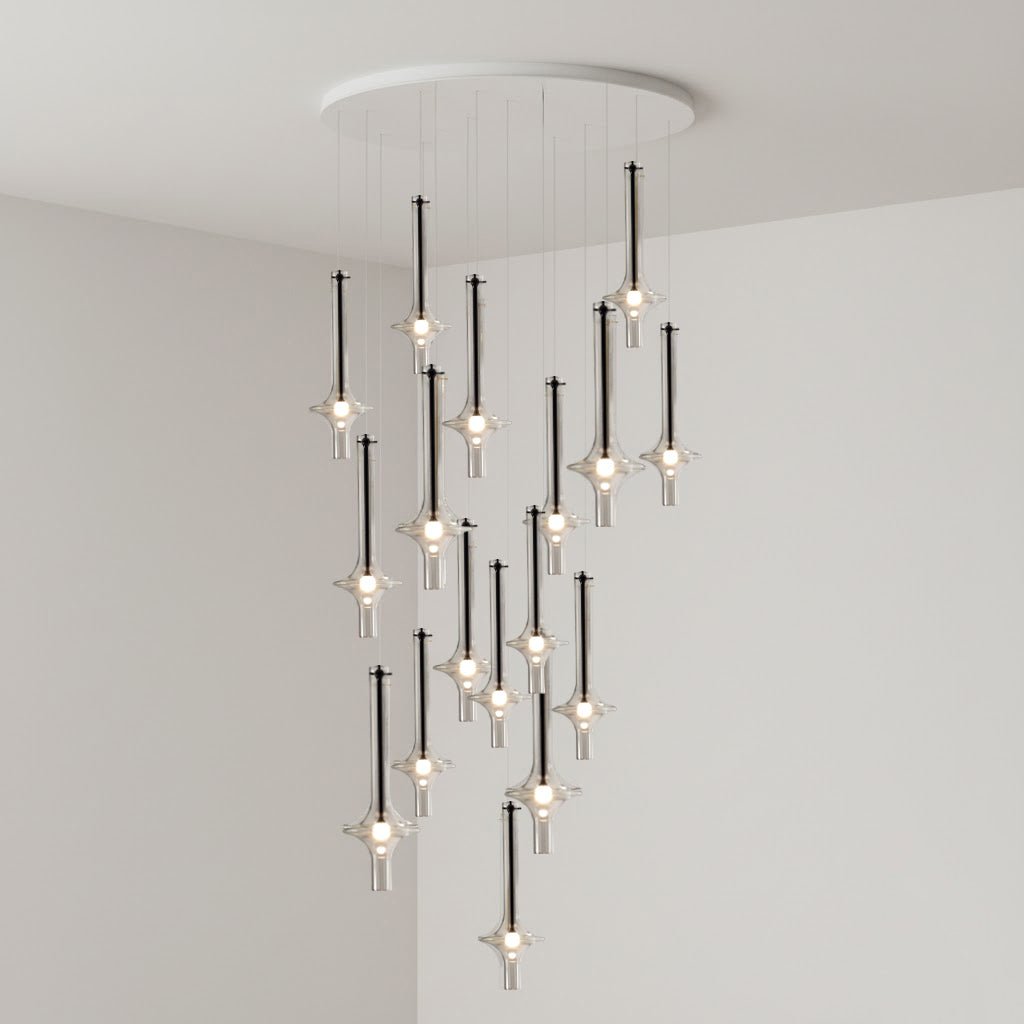 Black-stemmed Clérachic pendants in clear glass cascade from a round canopy, lit in the corner of a plain grey room.
