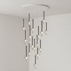 Black-stemmed Clérachic pendants in clear glass cascade from a round canopy, lit in the corner of a plain grey room.