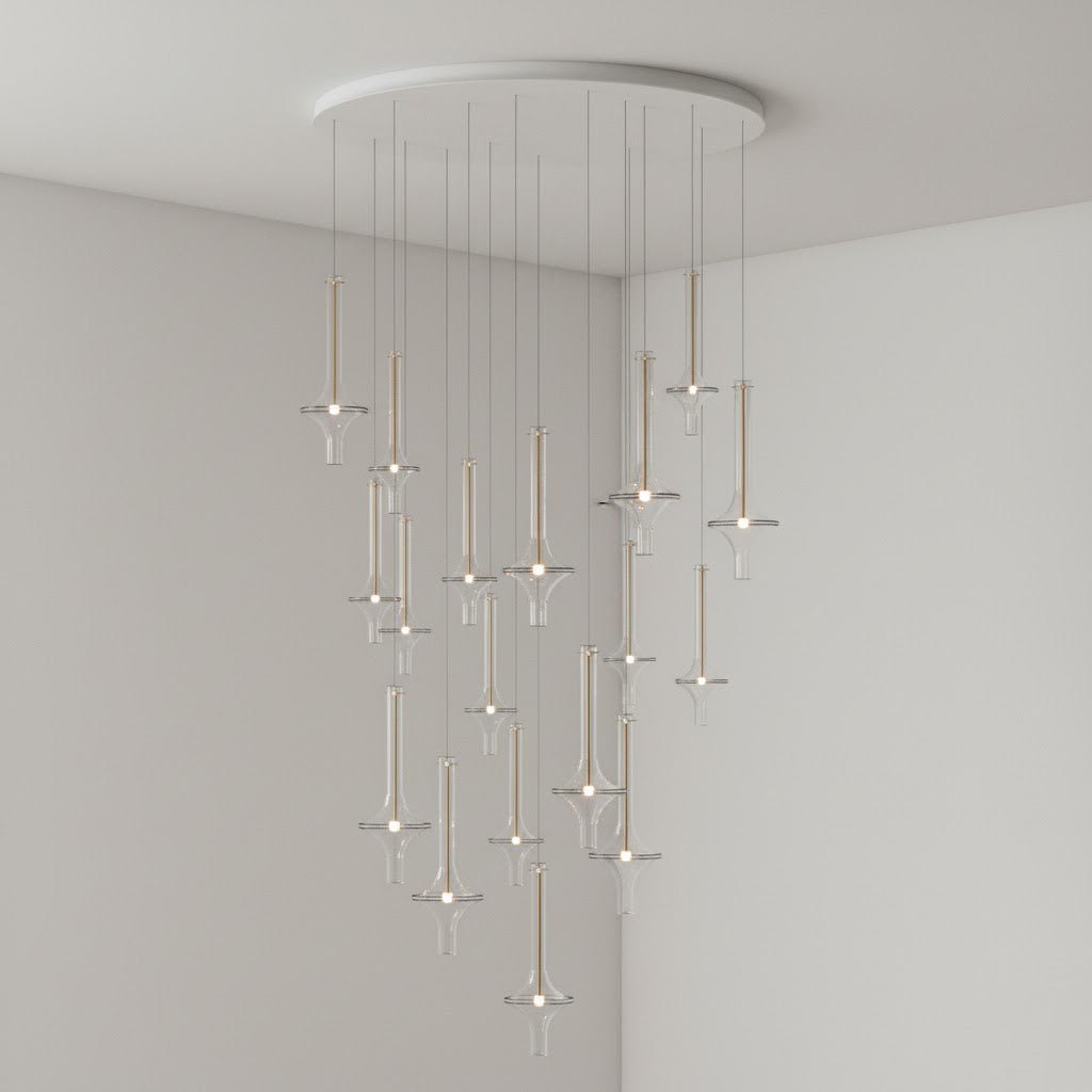 A wide cascade of lit Clérachic pendants in clear glass drops from a round canopy in the corner of a plain grey room.