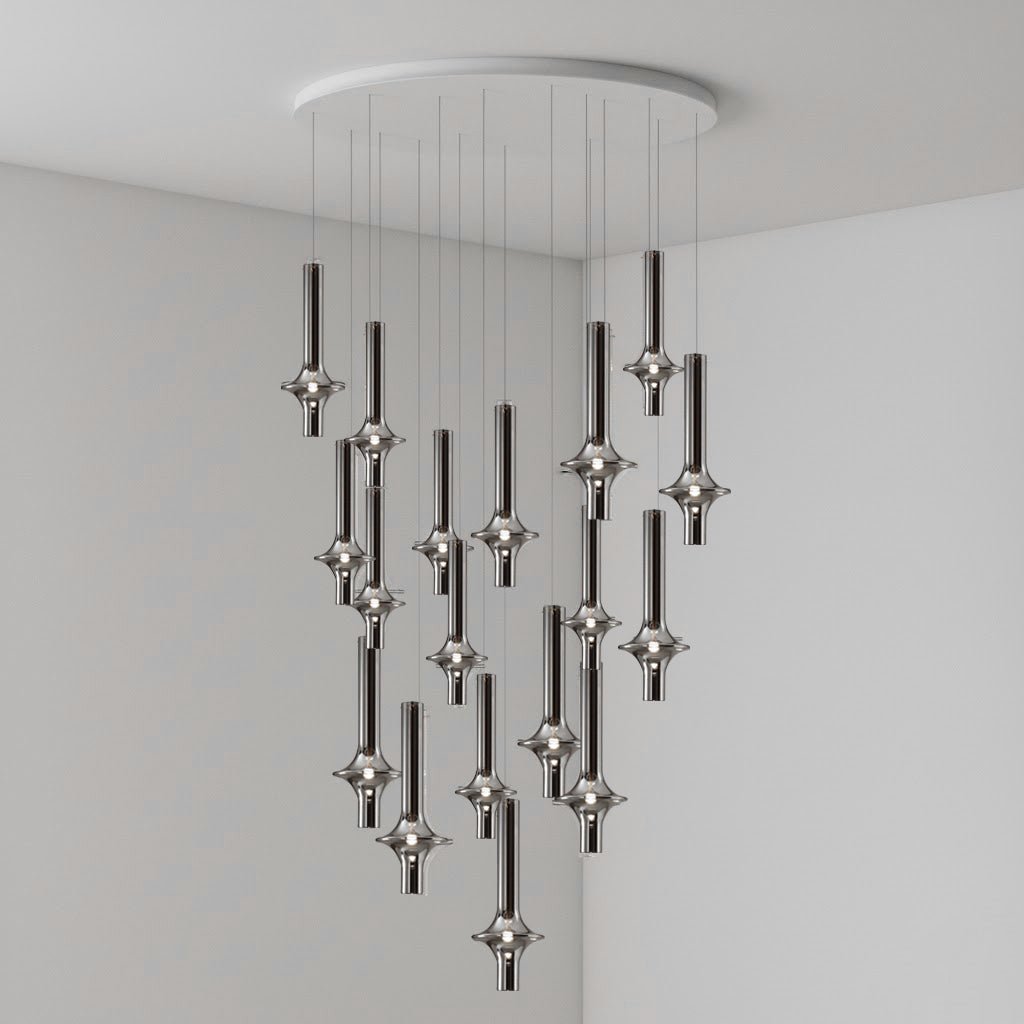 Black-stemmed Clérachic pendants cascade in an uneven spread from a round canopy, lit in the corner of a plain grey room.