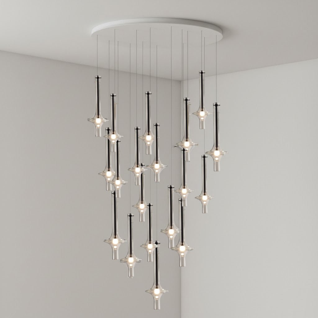 Black-stemmed Clérachic pendants hang with their lit bulb tips prominent, dropping from a round canopy in a grey corner room.