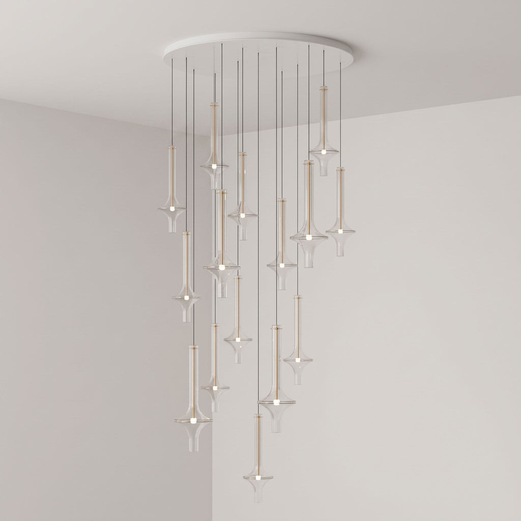 Gold-stemmed Clérachic pendants scatter vertically from a round canopy, lit in clear glass in the corner of a grey room.