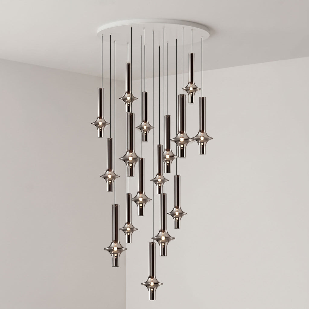 Black-stemmed Clérachic pendants gather toward the centre of their spread, lit in clear glass in a grey corner room.